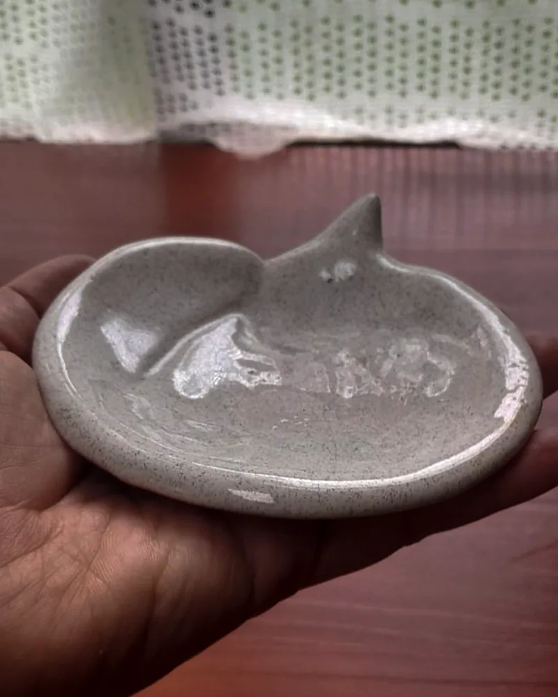 Un plato de cerámica gris moteado, apoyado en la palma de una mano