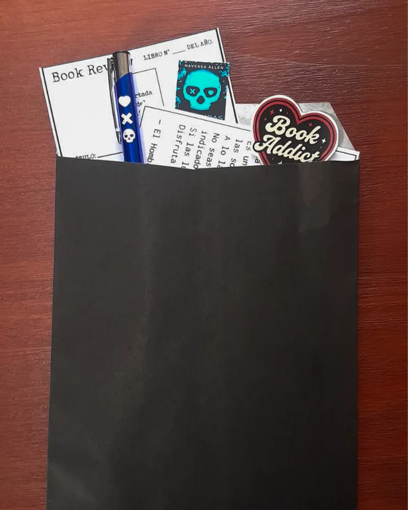 El sobre «Abrime» con una tarjeta para reseñar el libro, una birome, un sticker «Book Addict» y una calavera del libro